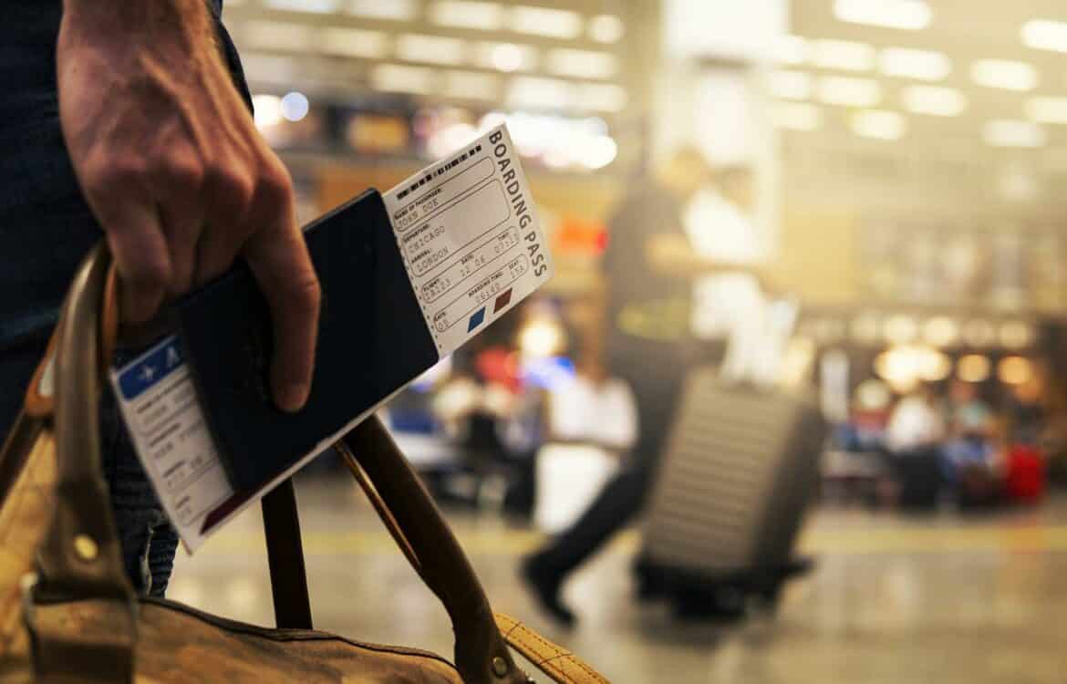 Pessoa no aeroporto segurando passaporte e bilhete
