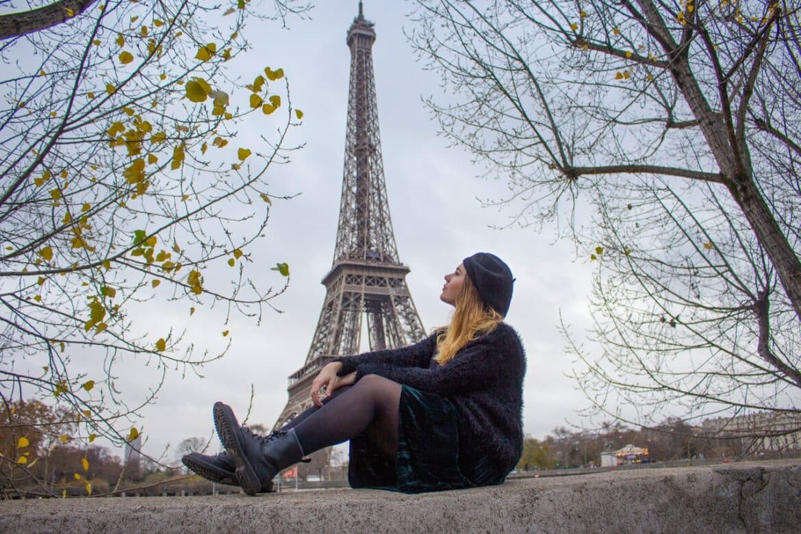 Mulher sozinha sentada com a Torre Eiffel ao fundo
